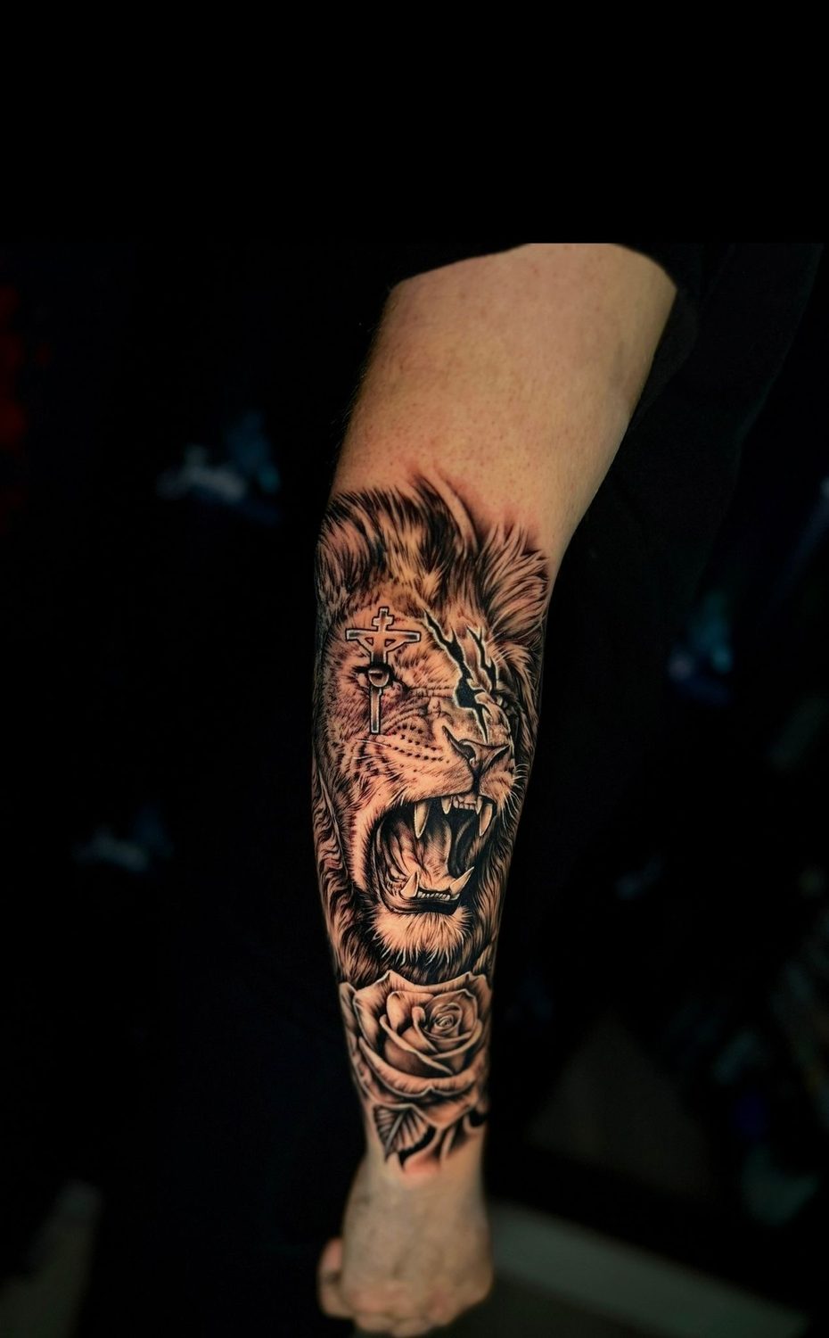 Black and grey lion with cross and rose forearm tattoo